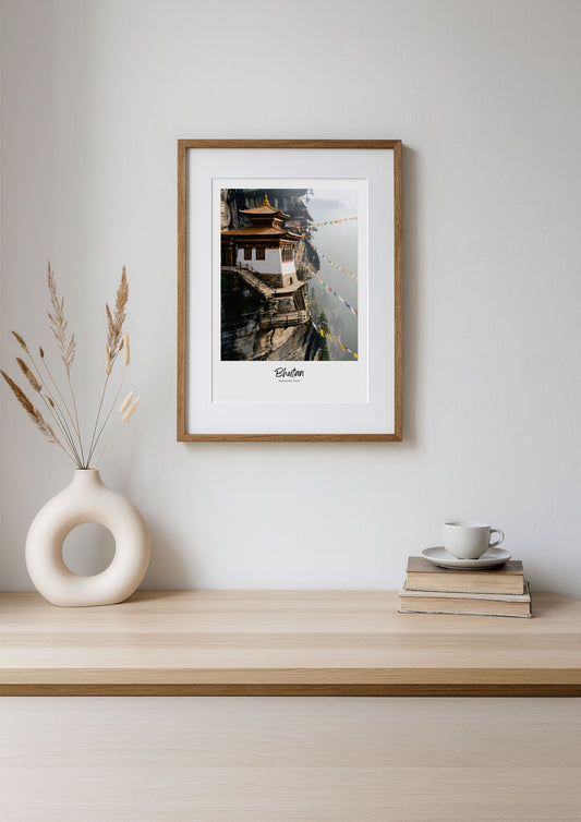 Framed photograph of a mountain village on a wooden shelf with decorative items.