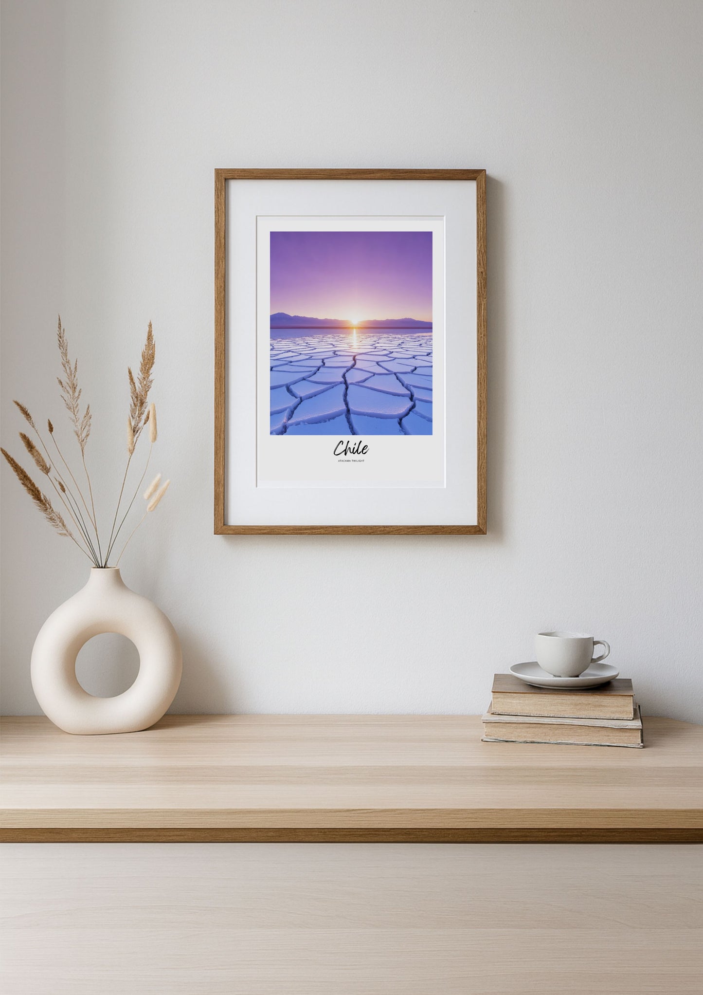 Framed artwork of a sunset over a desert landscape on a wooden shelf with decor items.