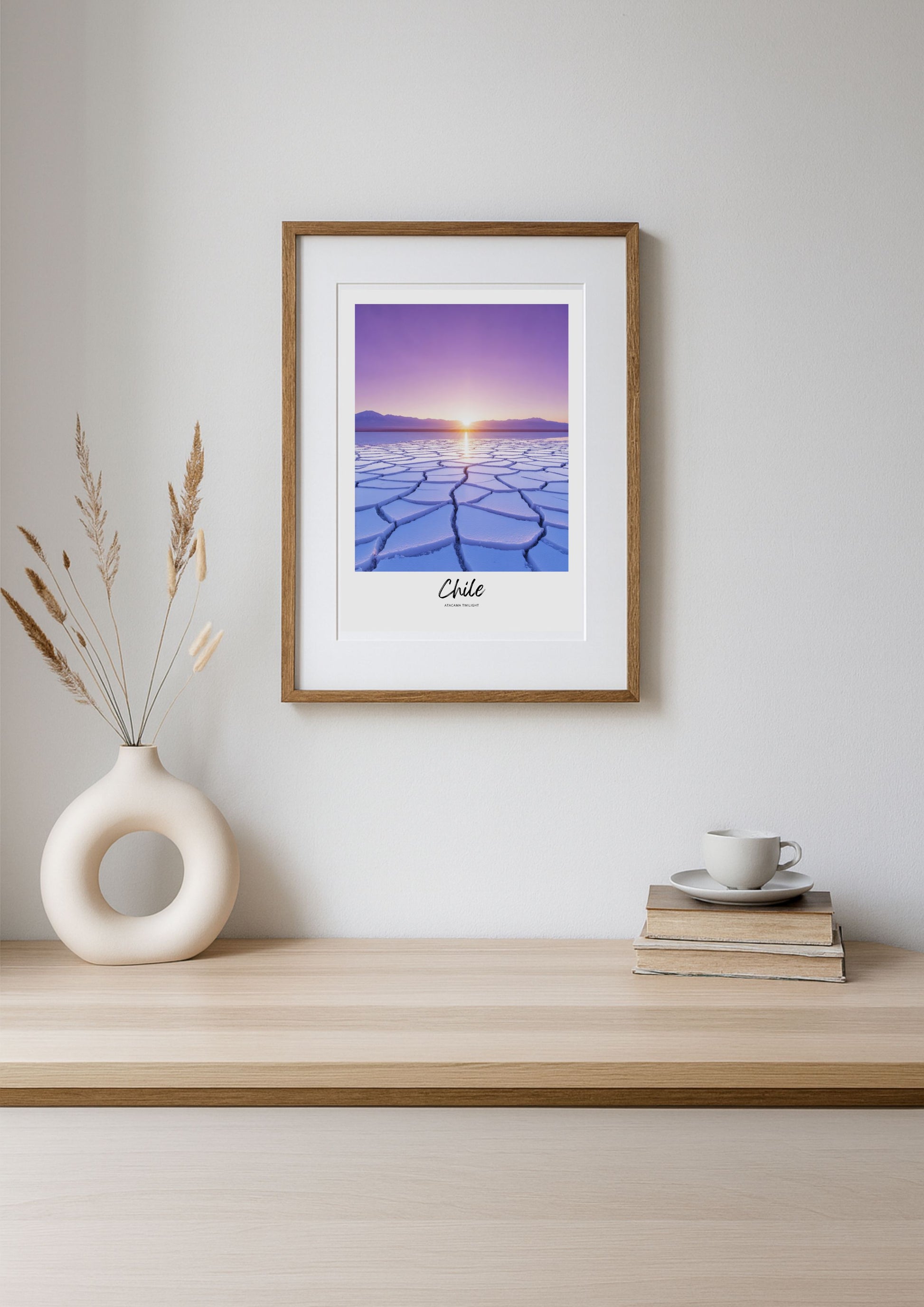 Framed artwork of a sunset over a desert landscape on a wooden shelf with decor items.