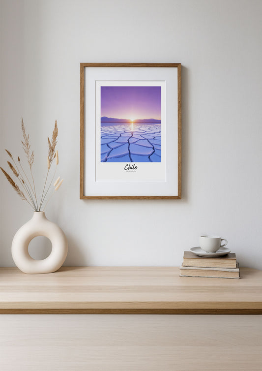 Framed artwork of a sunset over a desert landscape on a wooden shelf with decor items.