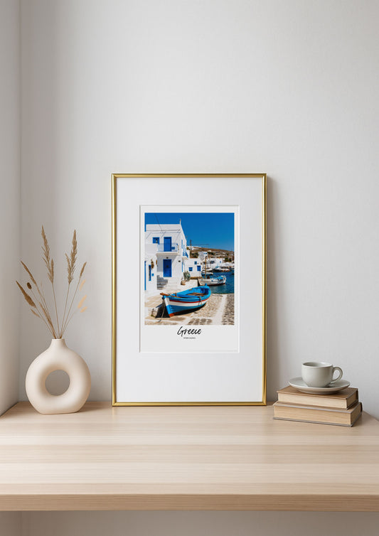 Framed photograph of a Greek island scene on a shelf with decor items.