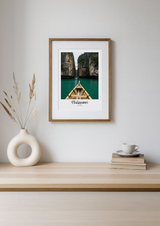 Framed photograph of a boat in a lagoon with 'Philippines' text on a wall above a wooden shelf.