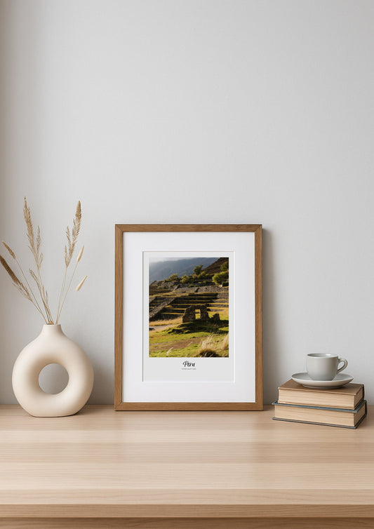 Framed print on a wooden shelf with a vase and books against a white wall