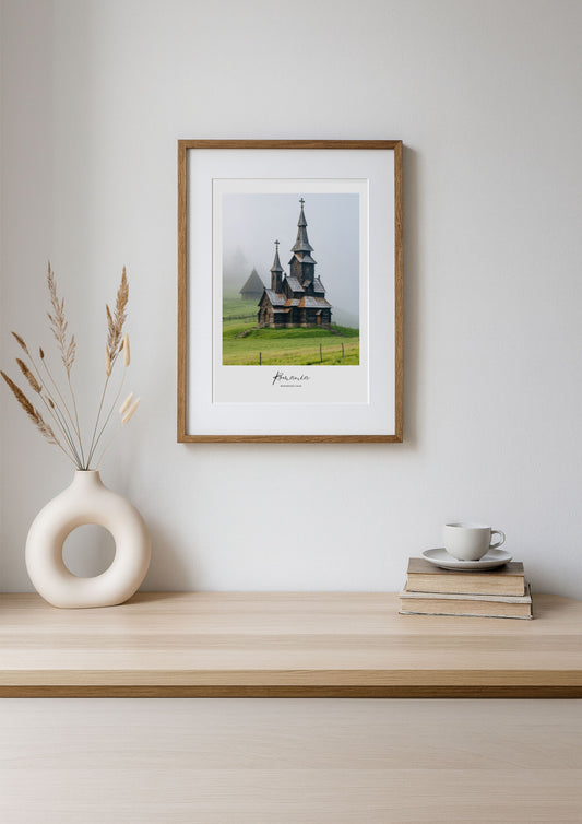 Framed photograph of a church in a field on a wooden shelf with decor items.