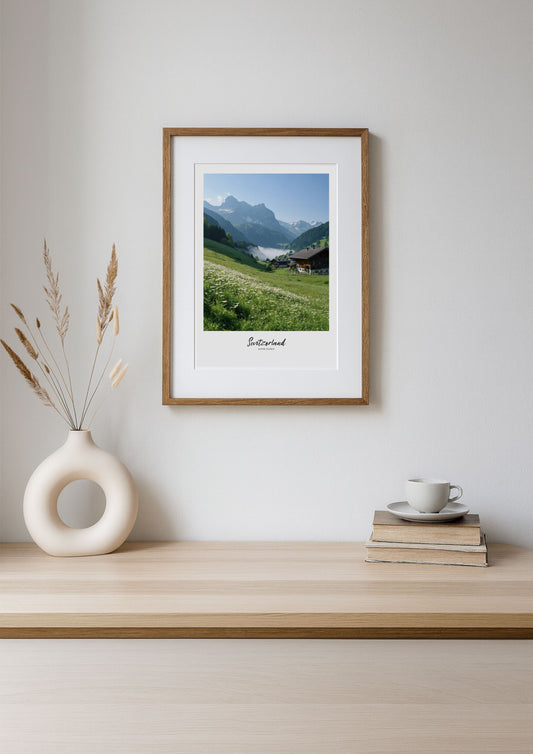 Framed print of a mountain landscape on a wooden shelf with decor items.