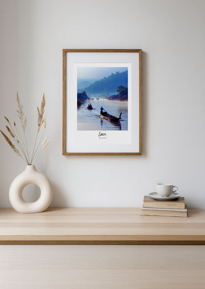 Framed photograph of a scenic landscape with a boat on a lake, displayed on a wooden shelf.