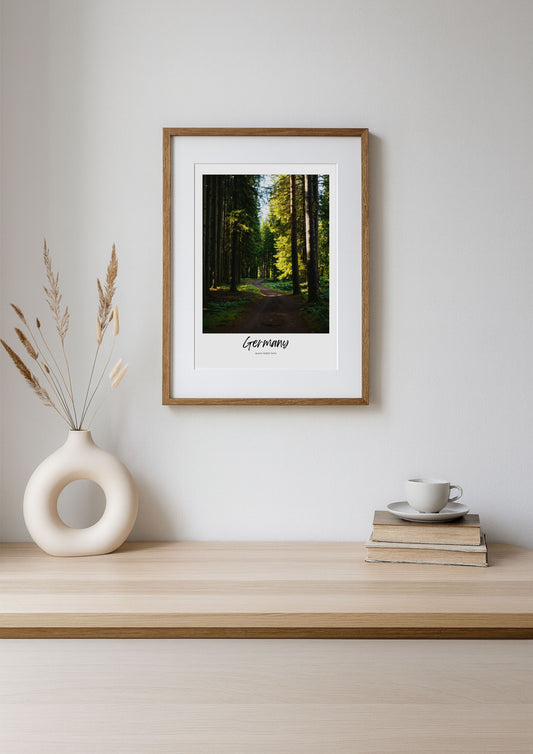 Framed print of a forest scene on a wooden shelf with decor items.