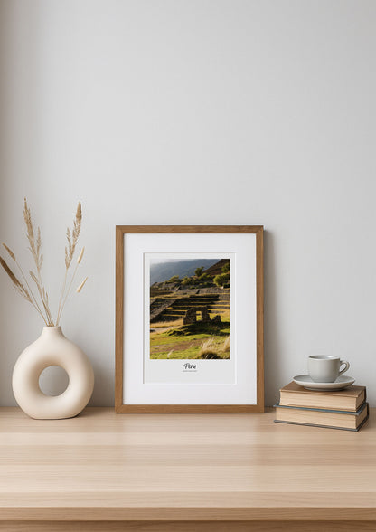 Framed print on a wooden shelf with a vase and books against a white wall
