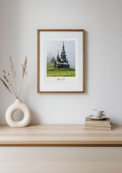Framed photograph of a church in a field on a wooden shelf with decor items.